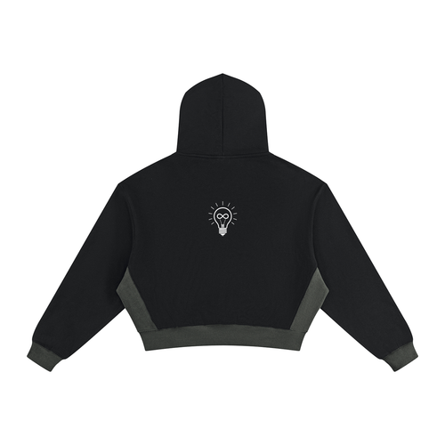 Black cropped hoodie with dark gray contrast panels on the sides and cuffs, featuring a small 'RISE LUXE' logo printed on the back center, shown against a plain white background.
